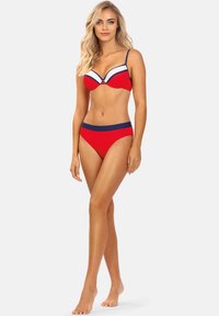 Czerwony kostium bikini z usztywnionym stanikiem z białymi i granatowymi akcentami. Majtki mają granatowy pas. Gładki materiał, bez wzorów.
