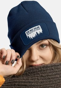Navy knit beanie with a rectangular patch featuring forest graphics and the text "ICH MAG BÄUME DIE HALTEN DIE FRESSE." Textured fabric.