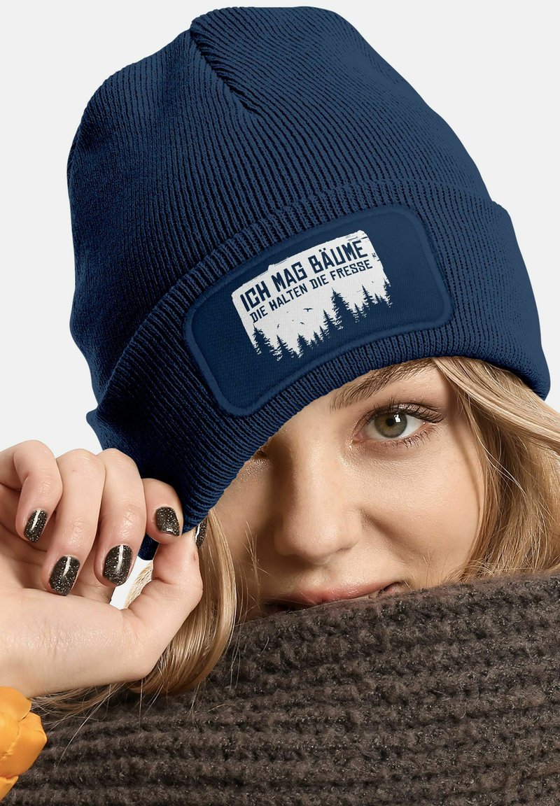Navy knit beanie with a rectangular patch featuring forest graphics and the text "ICH MAG BÄUME DIE HALTEN DIE FRESSE." Textured fabric.