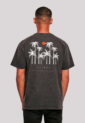 Schwarzes Baumwoll-T-Shirt mit einem weißen Palmbaum-Graphic und einer roten Sonne. Sichtbare Nähdetails und lockere Passform mit kurzen Ärmeln.