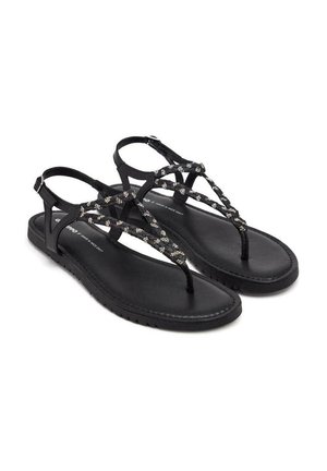 Sandalias negras con suela plana, que presentan una tira superior trenzada adornada con pequeños acentos metálicos. Diseño de talón abierto y con correa entre los dedos.