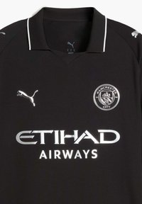 Črna nogometna majica s polo ovratnikom, ki vključuje srebrne logotipe: logotip Puma na levem prsnem delu in besedilo "ETIHAD AIRWAYS" spodaj.
