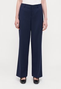 Marineblauwe wijde broek van gladde stof, met een vlakke voorkant en zijzakken. In combinatie met zwarte platte schoenen voor contrast.