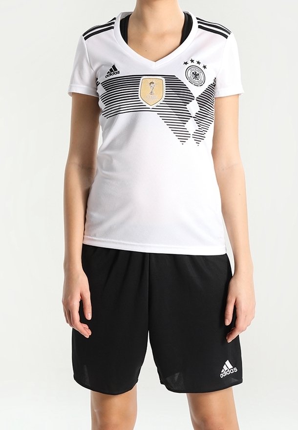 Bílý sportovní dres Adidas s černými pruhy a zlatým emblémem, doplněný černými šortkami s logem Adidas.