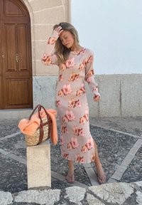 Kvetinové vzory, dlhý rukáv, šaty v svetloružovej farbe s odtieňmi oranžovej. Doplnené tkanou taškou a broskyňovým sveterom.