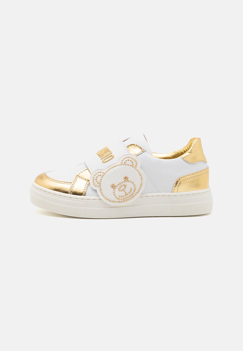Sneakers bianchi con dettagli dorati, caratterizzati da un design di orsetto con strass, una fascia in Velcro e una suola in gomma testurizzata.