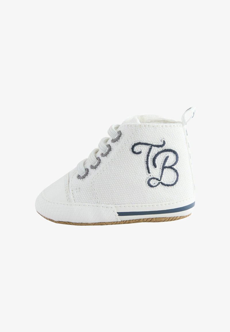 Chaussure bébé en tissu blanc avec des lacets blancs, broderie "TB" sur le côté, et semelle en caoutchouc avec une bande bleu marine.