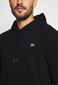 Felpa nera con cappuccio regolabile e un piccolo logo bianco sul petto. Realizzata in tessuto morbido e testurizzato, con una vestibilità classica.