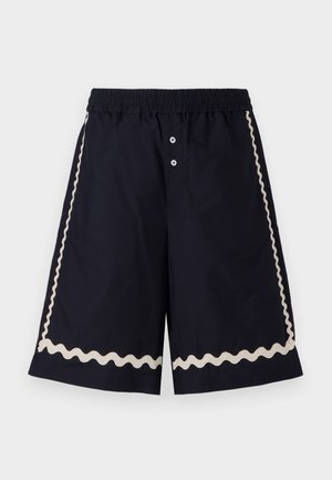 Navy shorts with an elastic waistband, two front buttons, and cream wavy trim along the sides. Lightweight fabric, knee-length design.