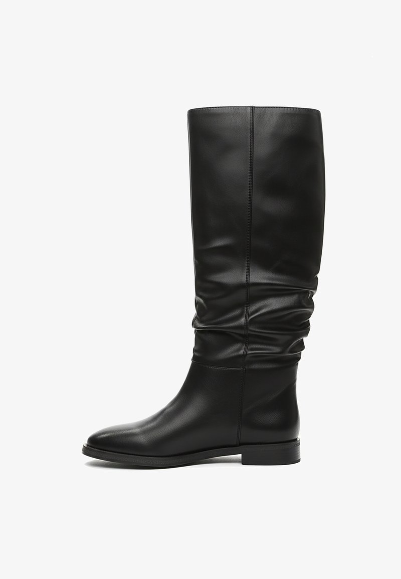 Bottes en cuir noires montant jusqu'aux genoux avec un design décontracté, une texture lisse, un bout arrondi et un talon bloc bas. Détail de couture le long de l'arrière.