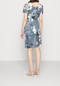 Robe fleurie à manches courtes et dos en V. Fabriquée en tissu bleu-gris orné de grandes fleurs multicolores. Silhouette ajustée.