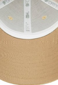 Beige Baseballcap mit strukturierendem Design, texturiertem Stoff und einem weißen Innenfutter, das Mesh- und Branding-Details sichtbar macht.