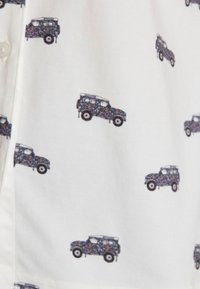 Krátky rukáv košeľa z bielej tkaniny s vzorom malých tmavomodrých vozidiel s kvetinovými motívmi, potlačeným rovnomerne po celom povrchu.