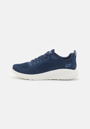 Baskets de sport bleu marine avec semelle blanche, dessus en mesh respirant, design à lacets et logo sur le talon et la languette.