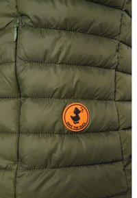 Giacca trapuntata verde oliva con una toppa circolare arancione che presenta la silhouette di un'anatra nera e il testo "SAVE THE DUCK".