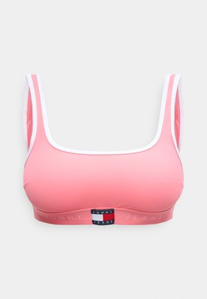 Sujetador deportivo rosa con ribete blanco y logo de Tommy Jeans en la banda frontal, con tirantes anchos y escote cuadrado.