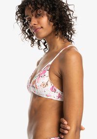 Bloemenbikini-top met een witte basis en roze en oranje bloemmotieven. Het ontwerp heeft dunne verstelbare bandjes en een driehoekige vorm.