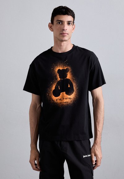 Zwarte katoenen t-shirt met een berenafbeelding in oranje en zwart, met de tekst "BEAR IN MIND" eronder. Relaxte pasvorm, korte mouwen.