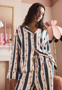 Gestreiftes Schlafanzug-Set in Weiß, Marineblau und Pink mit Sternmustern. Beinhaltet ein Hemd mit Knopfleiste und Tasche sowie eine Hose mit elastischem Bund.