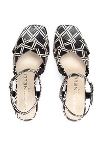 Tacones con tirantes en blanco y negro con un diseño estampado, punta cuadrada y hebilla en el tobillo, que presentan una parte superior texturizada y una plantilla suave de color beige.