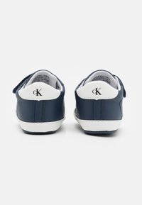 Granatowe skórzane sneakersy z białymi akcentami, z logo na pięcie i teksturowanym wnętrzem. Zapięcie na podwójny rzep.