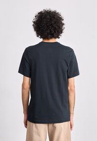 T-shirt preto de algodão com mangas curtas, decote redondo e um ajuste descontraído. Textura suave, sem padrões ou detalhes visíveis nas costas.