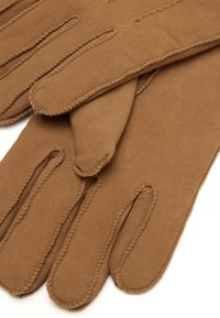Guanti in suede marrone con design a cinque dita, caratterizzati da cuciture visibili e una consistenza morbida. Il tessuto appare liscio e caldo.