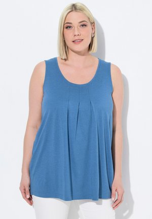 Top blu senza maniche realizzato in tessuto morbido, caratterizzato da un collo a giro e un design plissettato sul davanti. Abbinato a pantaloni bianchi.