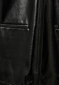 Must must nahkkasärk, millel on sile tekstuur ja kerge läige, vertikaalsed õmblused ning kaks horisontaalset taskut.