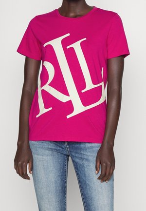 Fuksiansävyinen puuvillainen t-paita, jossa iso valkoinen tekstisuunnittelu. Lyhyet hihat, pyöreä kaula-aukko, rento istuvuus ja sileä pinta. Yhdistetty sinisiin farkkuihin.