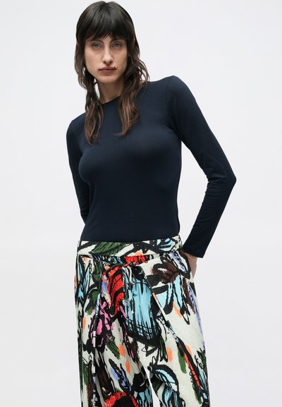 Μπλε ναυτικό τοπ με μακρύ μανίκι, συνδυασμένο με πολύχρωμη φούστα με έντονα λουλουδένια σχέδια σε διάφορα χρώματα και μέση με κορδόνι.