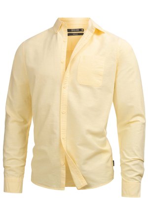 Camicia giallo chiaro a maniche lunghe con bottoni, taschino sul petto, colletto aperto e etichetta del marchio visibile all'interno del colletto.