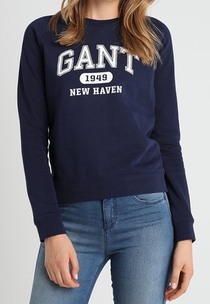 Námořnická modrá mikina vyrobená z bavlny, s kulatým výstřihem, žebrovanými manžetami a lemem, s bílým textem "GANT 1949 NEW HAVEN."