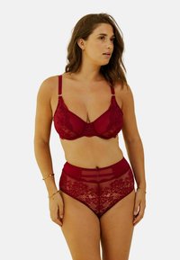 Ensemble de soutien-gorge en dentelle rouge et culotte taille haute avec des motifs floraux, des panneaux transparents et des accents en métal doré. Fini lisse.