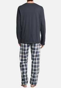 Chemise en coton bleu marine à manches longues associée à un pantalon de pyjama en flanelle à carreaux bleu, blanc et gris, offrant une coupe décontractée et un style confortable.