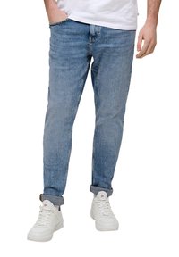 Jasnoniebieskie dżinsy o slim fit, z wyblakłą fakturą, podwiniętymi mankietami i klasycznym pięciopocketowym fasonem, w połączeniu z białymi trampkami.