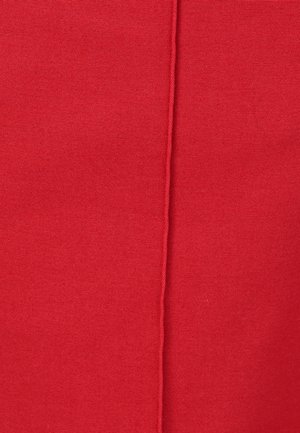 Primer plano de una tela roja texturizada con una costura vertical prominente que corre por el centro.