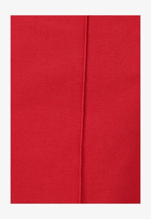 Primo piano di un tessuto rosso strutturato con una cucitura verticale prominente che corre lungo il centro.