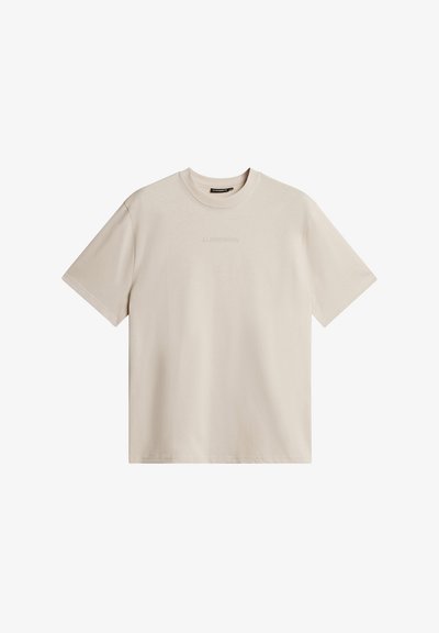 Svijetlosmeđa majica kratkih rukava od mekanog pamuka, s okruglim izrezom i diskretnim reljefnim logotipom sprijeda. Glatka, ujednačena tekstura.