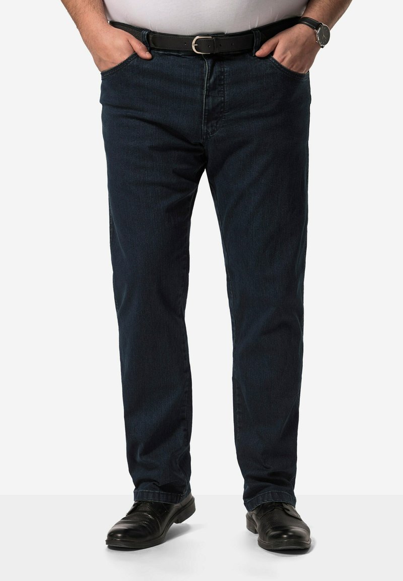 Jeans de mezclilla azul oscuro con corte recto, bolsillos delanteros y un cinturón de piel negro. Usados con zapatos de vestir negros.