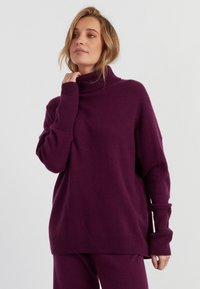Overmaatse paarse coltrui met geribde manchetten en zoom, gemaakt van een zachte, gestructureerde stof. Ontspannen pasvorm met zijsplitten.