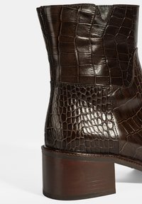 Braune Leder-Ankelboots mit einer strukturierten Krokodilprägung, einem schmalen Absatz und einem leichten V-Ausschnitt-Design oben.