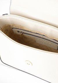 Borsa in pelle bianca aperta con foderatura interna beige visibile, piccola tasca con zip e chiusura a bottone magnetico.