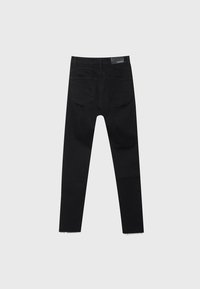 Pantalones de mezclilla negra con dos bolsillos traseros, pasadores para cinturón, un parche de cuero de marca en la cintura y bordes de tobillo sin rematar.