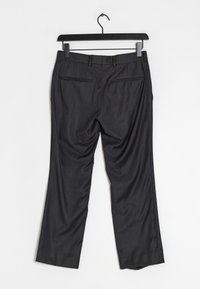 Tmavě šedé kalhoty na míru s plochým předním dílem, dvěma zadními kapsami a jemným kostkovaným vzorem, zavě šené na černém ramínku.