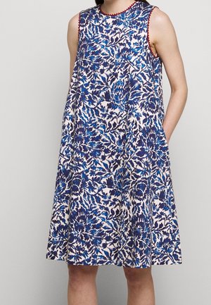 Mouwloze jurk met bloemendessin in marineblauw en wit, voorzien van rode bies langs de halslijn, met zijzakken en een uitlopende silhouet.