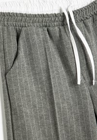 Grå stribede sweatpants har et struktureret stof, elastisk talje med hvide snore og sidelommer.