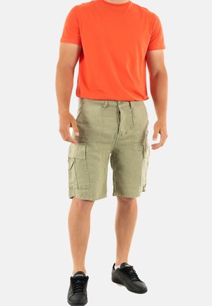 Olijfgroene cargo shorts met zijzakken, gecombineerd met een feloranje T-shirt en zwarte sneakers, staand op een neutrale achtergrond.