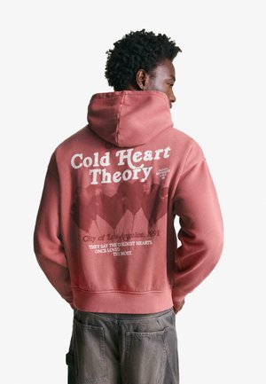 Felpa rosa con una grande stampa grafica sul retro, che presenta testo e silhouette di montagne. Ha una tasca a marsupio anteriore e un cappuccio.