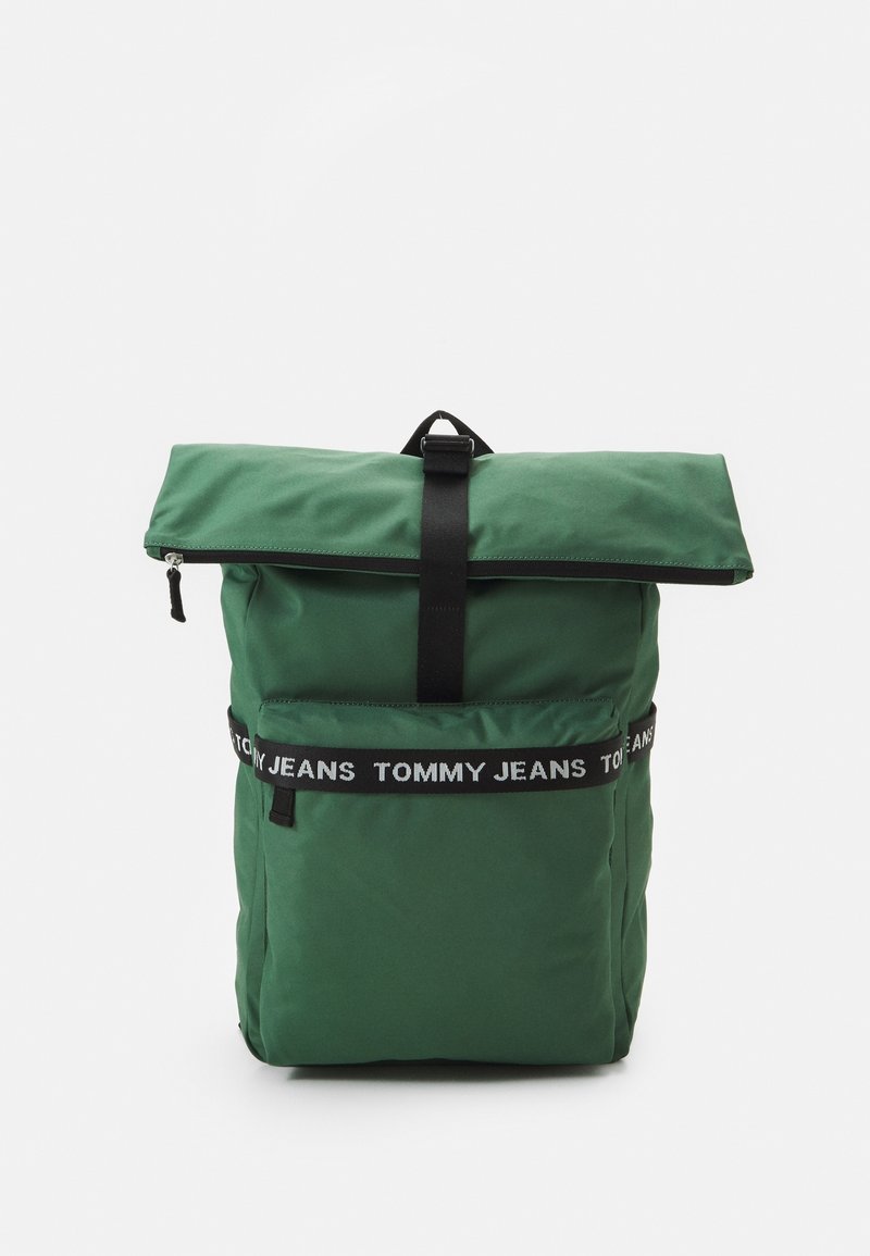Grøn roll-top rygsæk med sort strop og forlompe med et sort-hvidt bånd med "TOMMY JEANS" logo.